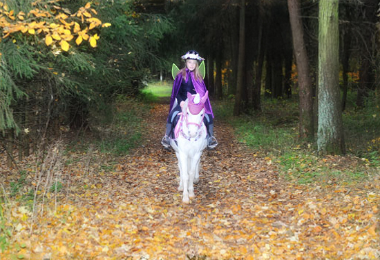 Bild eines Kindes, das als Waldelfe verkleidet auf einem Pony reitet