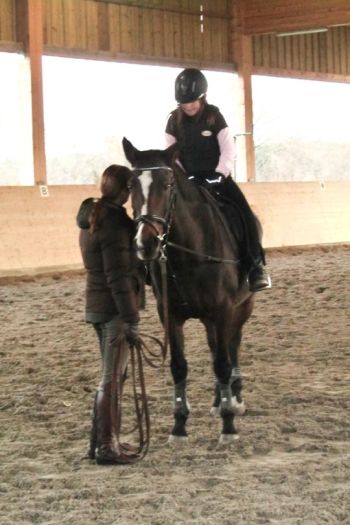 Bild einer Reitschülerin auf einem Pferd mit erwachsender Person